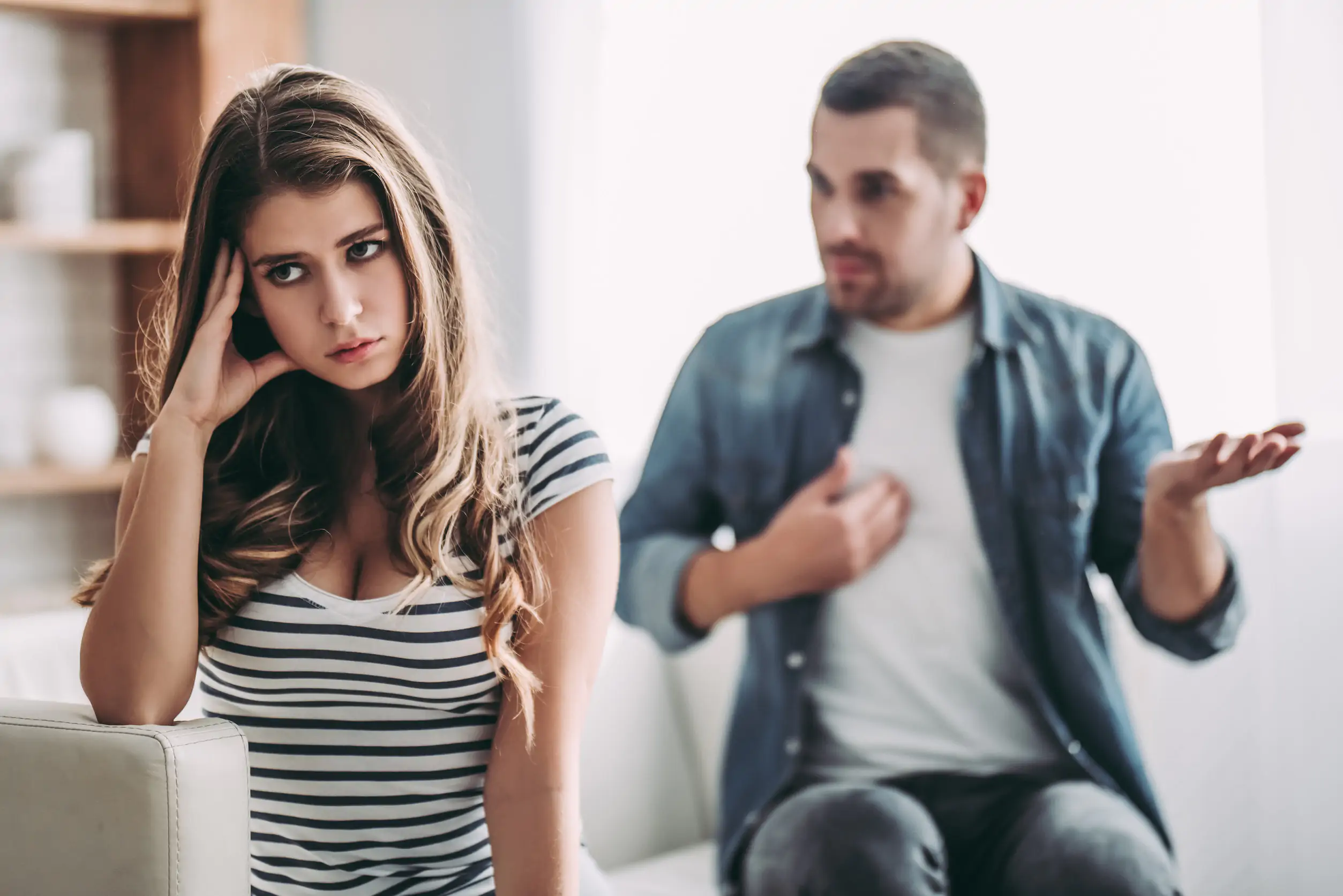 Upset couple at home. Handsome man and beautiful young woman are having quarrel. Sitting on sofa together. Family problems. advice for newlyweds